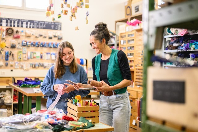 Claudia Hürlimann und eine Jugendliche halten Bänder und Maltuben in den Händen.